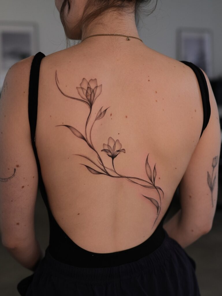 Fine Line Floral Tattoo Flowing Across Back Tattoo Design