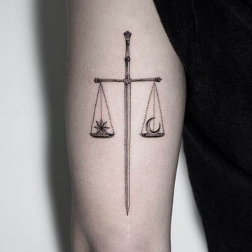 This tattoo features a vertical sword as the central axis, with balanced scales suspended from each side.