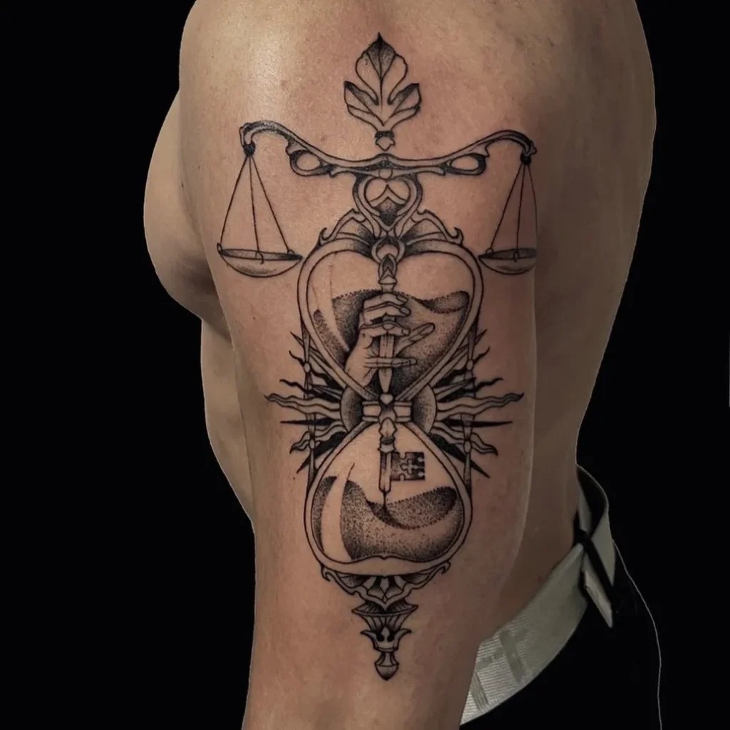 This beautifully detailed tattoo showcases a combination of a symbolic hourglass entwined with the Libra scales, emphasizing the themes of balance and the passage of time.