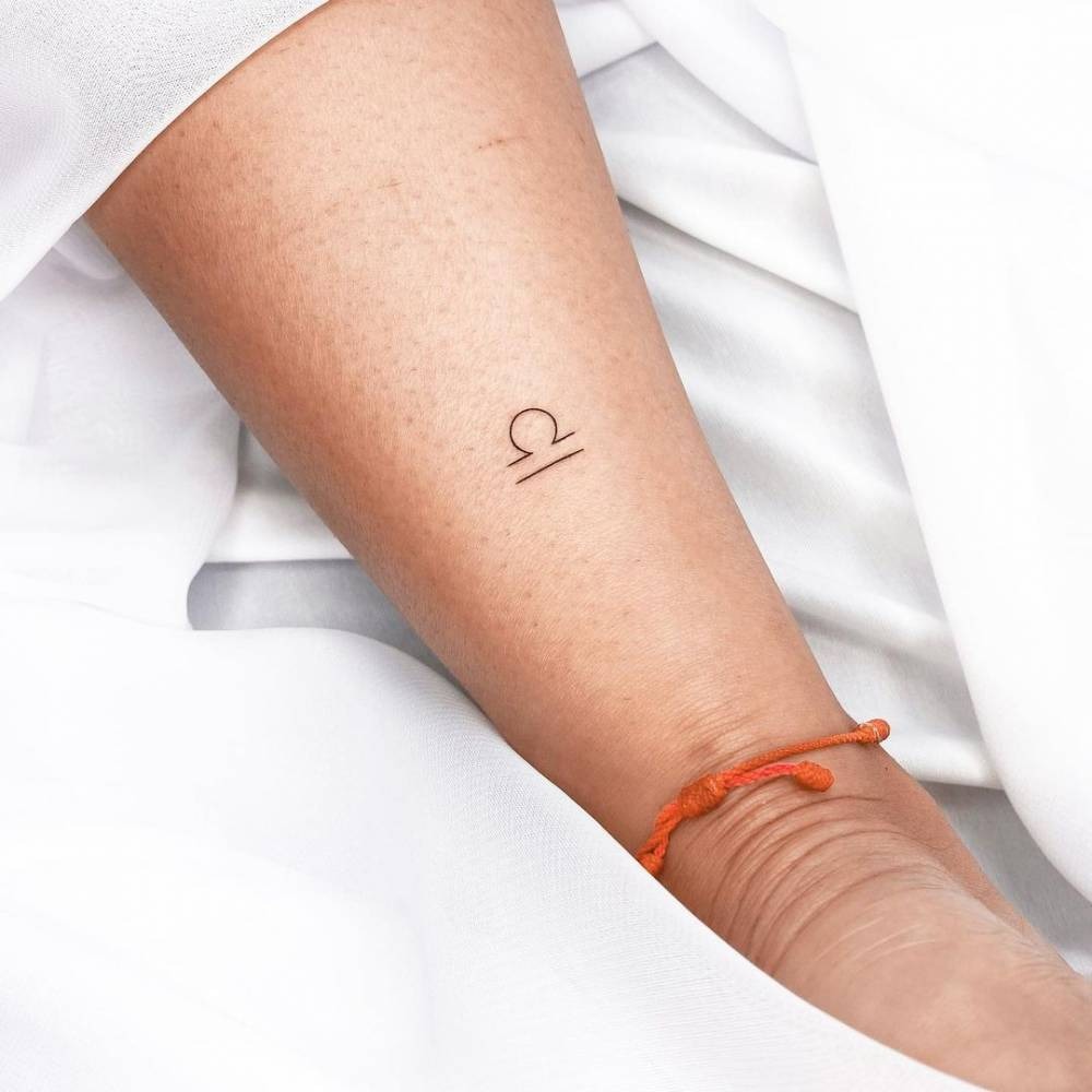 Showing the clean lines of the Libra symbol on the forearm, this tattoo exudes elegance and simplicity.