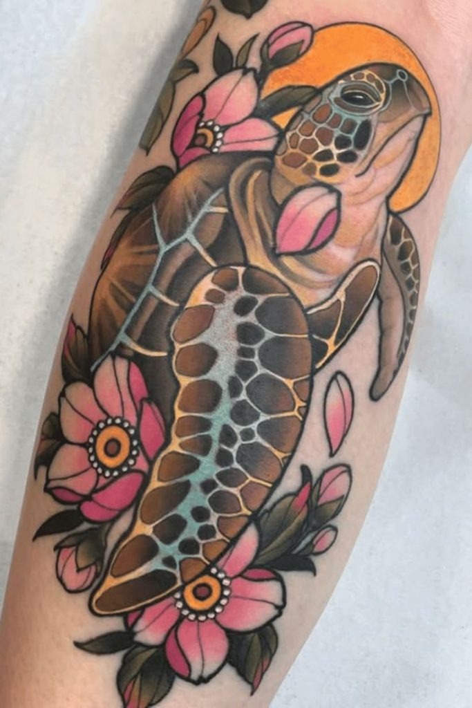 A bold tattoo features a bright green turtle in a composition with pink flowers.