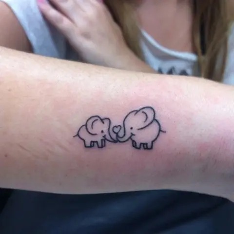 This delightful tattoo of two elephants, one large and one small, shows a heartwarming connection between the two animals, symbolizing love, care, and family.