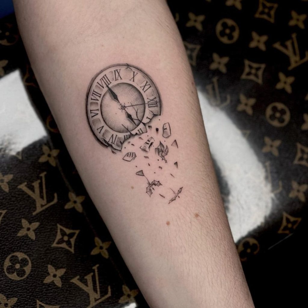 A minimalist yet powerful tattoo of a clock breaking into pieces, symbolizing the inevitability of change and the fleeting nature of time.