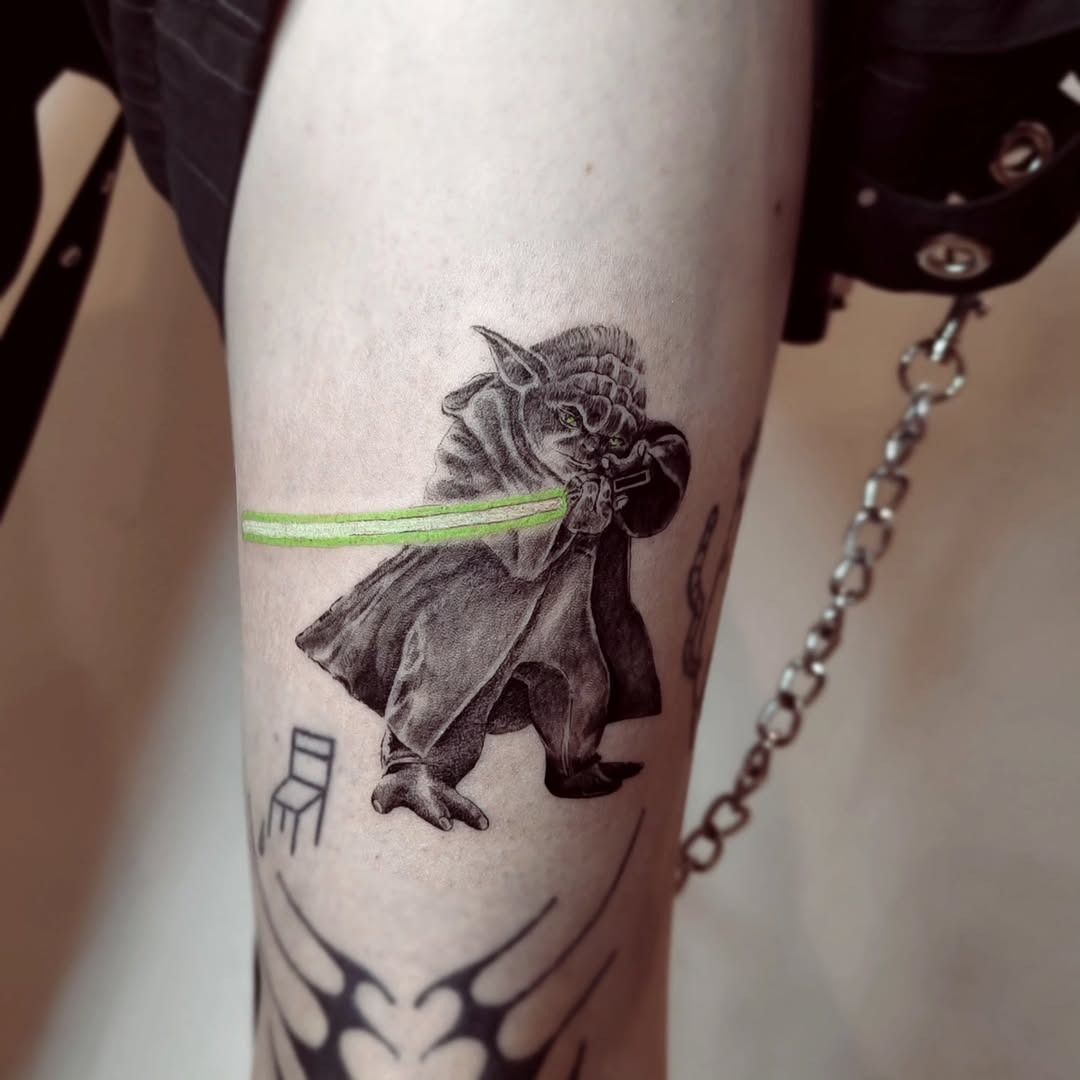 Intricate Yoda tattoo featuring a lightsaber Tattoo Design