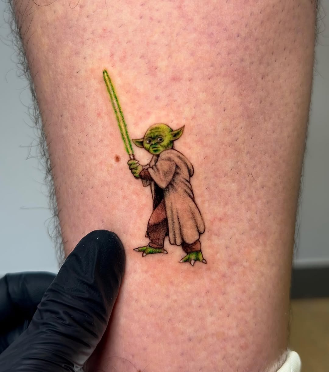 Playful Yoda with lightsaber tattoo on skin Tattoo Design
